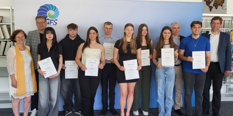 Ausgezeichnete Schüler mit zwei Lehrern zeigen ihre Urkunden